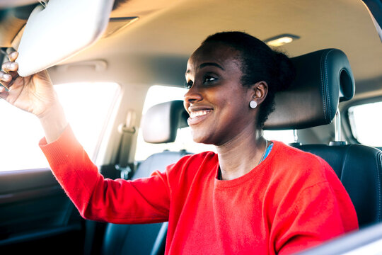Smiling ethnic lady looking in mirror in car