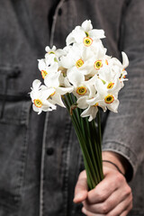 Man holds a bouquet of white daffodils in his hand. Close up.