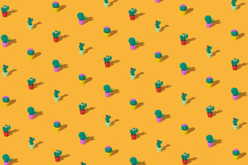 Pattern of toy green cacti on a bright yellow background