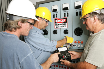 Group of electricians using an OHM meter to test voltage in an industrial power center.  All work being performed according to industry code and safety standards.  (note to inspector: OHMS on the mete