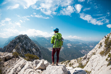 climber stands on top of the mountain. girl climber in a helmet and with a backpack mountains. Turkey.