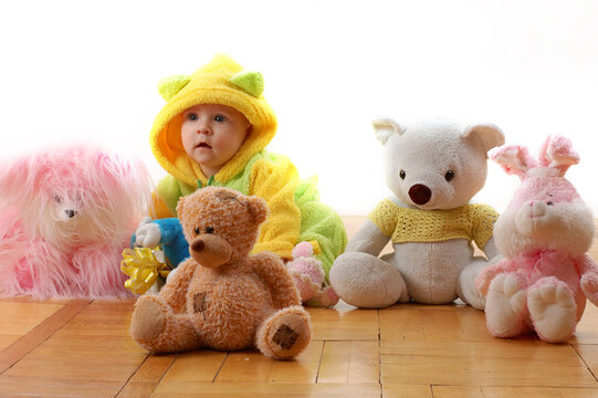 a baby sittig between toys and looking like one of theese toys