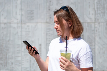 young woman drinking mojito and talking on the phone in summer in the city