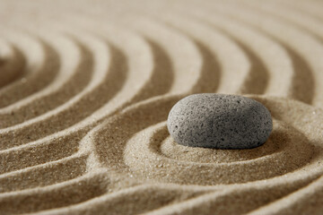 Fototapeta na wymiar Close-up stone on raked sand; zen cocept