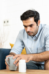 Unhappy man thinking about health or something bad on his sofa at home in the living room. upset man having problems, side view, copy space. Loneliness, depression, financial hangover concept.