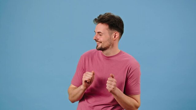 Young man enjoices dancing to music with happy smile
