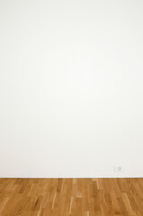 Blank white wall in a clean room with wooden floor - insert your own design on the wall