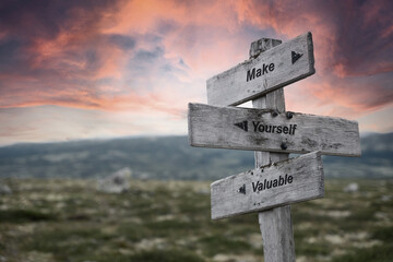make yourself valueable text quote on wooden signpost outdoors in nature. Pink dramatic skies in...