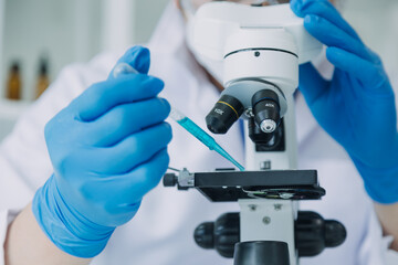 Medical Development Laboratory: Caucasian Female Scientist Looking Under Microscope, Analyzes Petri...