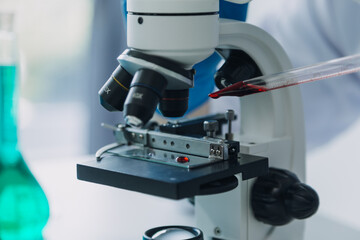 Medical Development Laboratory: Caucasian Female Scientist Looking Under Microscope, Analyzes Petri Dish Sample. Specialists Working on Medicine, Biotechnology Research in Advanced Pharma Lab