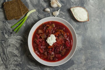 Red borscht soup with sour cream in a white plate