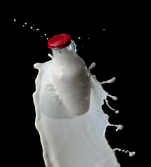 Full milk bottle with milk splashes isolated on black background - 600826931