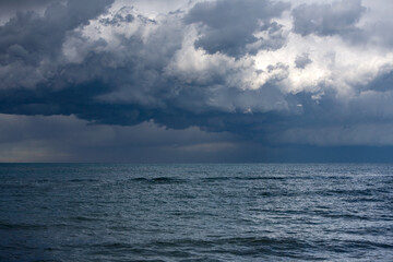 Naklejka na ściany i meble Landscape photo of dark grey thunderstorm clouds over the sea