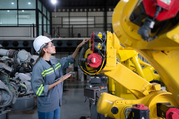 A female engineer installs a program on a robotics arm in a robot warehouse. And test the operation...