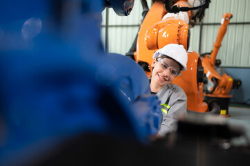In the robots warehouse, A female engineer inspects the electrical system of every robotics arm,...