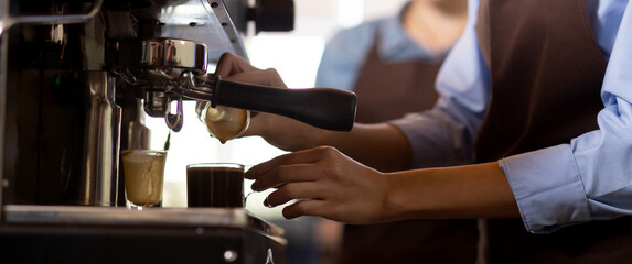 Closeup hands of barista preparing making coffee cappuccino or latte while pouring milk in coffee cup in cafe, close-up young asian woman making beverage on mug in coffeeshop, small business or SME.