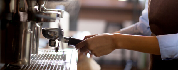 Closeup hands of young asian woman holding coffee grinder powder while mashed for preparing making coffee in cafe, barista using coffeemaker for making black coffee, small business or SME.