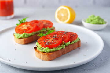 Vegan sandwich with avocado and tomatoes on a white dish