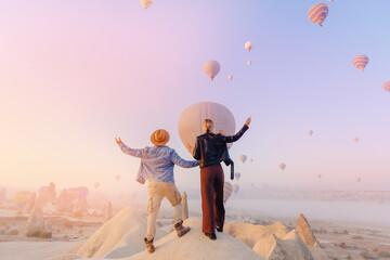 Couple lovers tourist in Cappadocia with colorful hot air balloon with sun light. Concept banner...