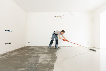 Master with needle roller for new screed concrete with mixture of cement for leveling for floors....