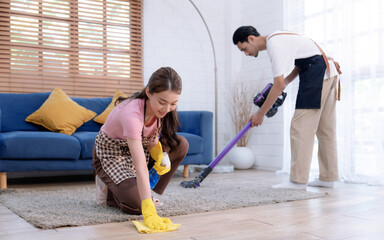 Happy young asian couple cleaning house together.