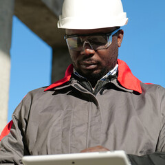 African american worker with tablet computer stands at construction site