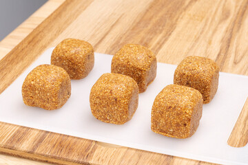 Energy balls candies made from natural products, square shape, on a cutting board. 