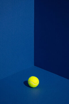 Tennis ball in the corner of blue walls. Minimal creative sport concept.