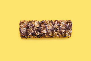 Muesli chocolate bar on a yellow background. Healthy sweet dessert snack. Cereal muesli with nuts, chocolate and berries on a yellow background. Carbohydrate bar for energy replenishment.