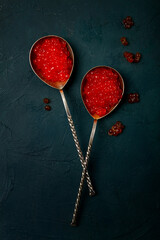 Spoons with red caviar, imitation, on a dark background, no people,