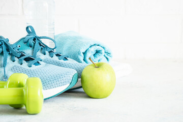 Fitness equipment on white. Sneakers, dumbbells and green apple. Training, workout and fitness concept.