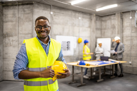 Portrait of Afro - American construction engineer standing inside building site.