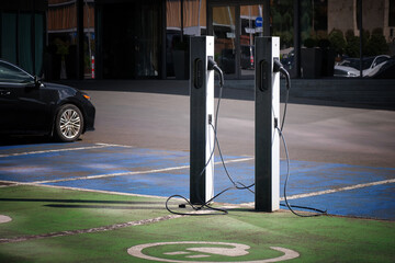 Close-up of an electric car charging station in the city against the backdrop of an office building