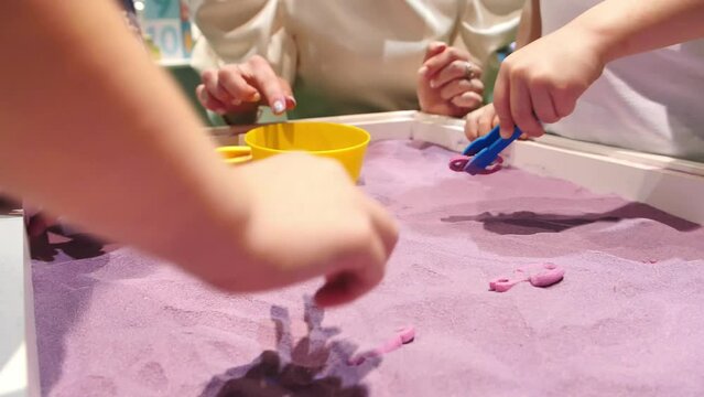 Child's hands playing with colorful magiс sand. Kids playing with sand and plastic toys. Sensory development and experiences, themed activities with children, fine motor skills development