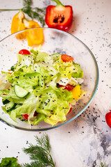 Vegetarian salad with fresh vegetables, lettuce and sesame seeds with tomatoes in a deep glass cup