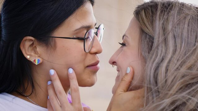 Close up young lesbian women couple kissing affectionately on gay pride festival day. Same sex loving relationships people. Generation z and homosexuality. 