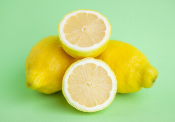 Limones grandes apilados junto a dos mitades de limón para hacer zumo de limón.