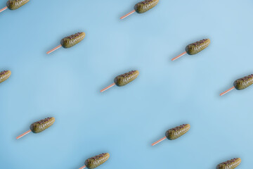 Trendy pattern made of green cucumber ice cream with strewed sprinkles on a pastel blue background. Minimal summer food concept.