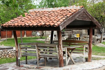Fototapeta na wymiar Summer house in the shape of a house, wooden benches, red tiles