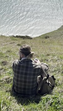 a white man with a beard and a backpack spends time along the ocean