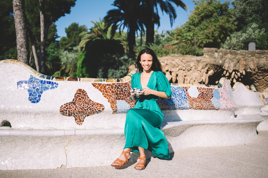 Cheerful woman sitting on bench with camera