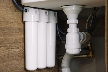 Home water filtration plant close-up. Small water filters under the sink in the kitchen