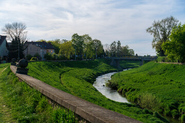 Fototapeta na wymiar River flowing through lush green urban area, Krakow city, spring evening, curvilinear city architecture, spring early morning, sustainable development in unity with nature