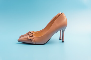 Naklejka premium Elegant and graceful beige women's shoes stand sideways on a blue background