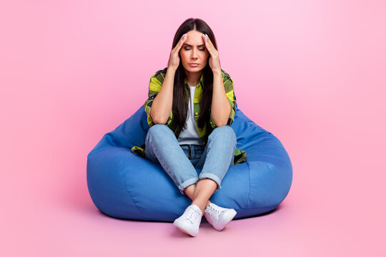 Full length photo of unhappy stressed lady wear checkered jackets head having pain sitting bean bag isolated pink color background