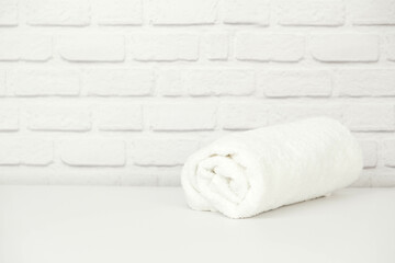 White moss twisted towel on white and brick background.