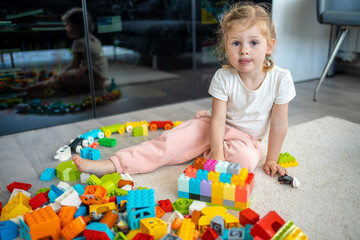 Little girl play with constructor toy on floor in home, educational game, spending leisure activities time concept
