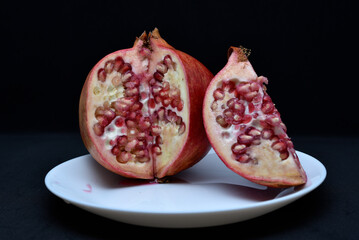 Pomegranate fruit on a white plate. Delicious pomegranate fruit. Cut fruit.