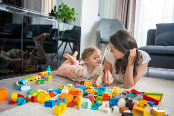 Little girl play with constructor toy on floor in home with mom or woman babysitter, educational...