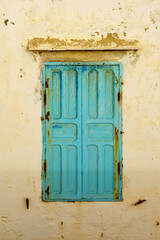 Blue windows and shutters on an old house white wall